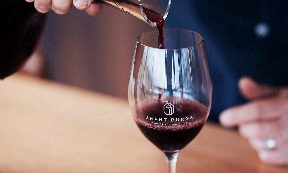 Close up image of a Grant Burge branded wine glass being filled with red wine