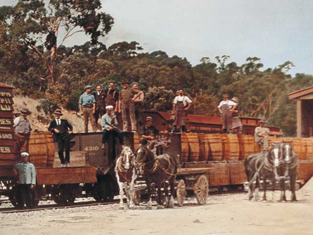 Workers pose on and in front of barrels loaded on to a train