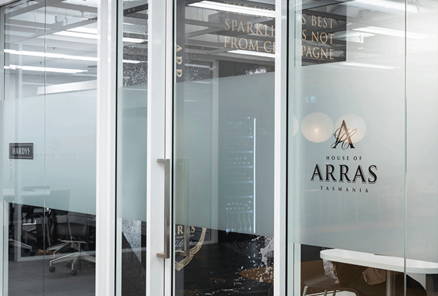 Sliding glass door in an office building with the House of Arras logo on the front