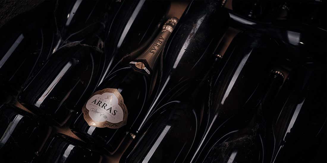 bottles of house of arras sparkling wine stacked