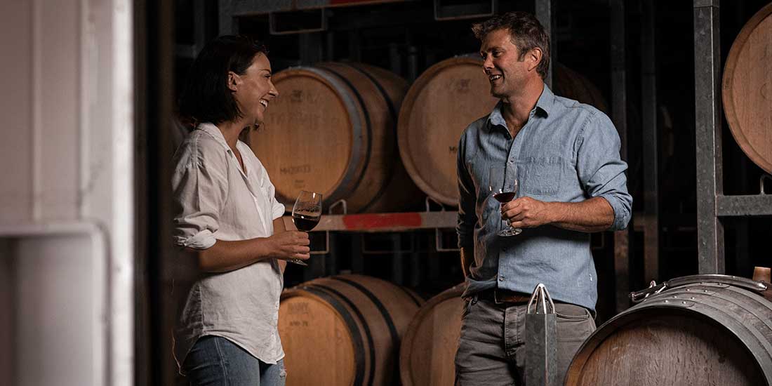 two winemakers hold glasses in a wine cellar
