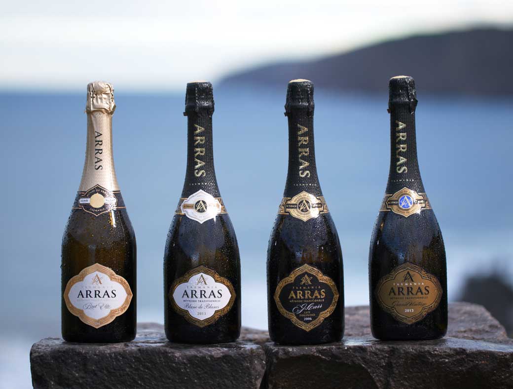 four bottles of house of arras win sitting on a stone table in front of the sea
