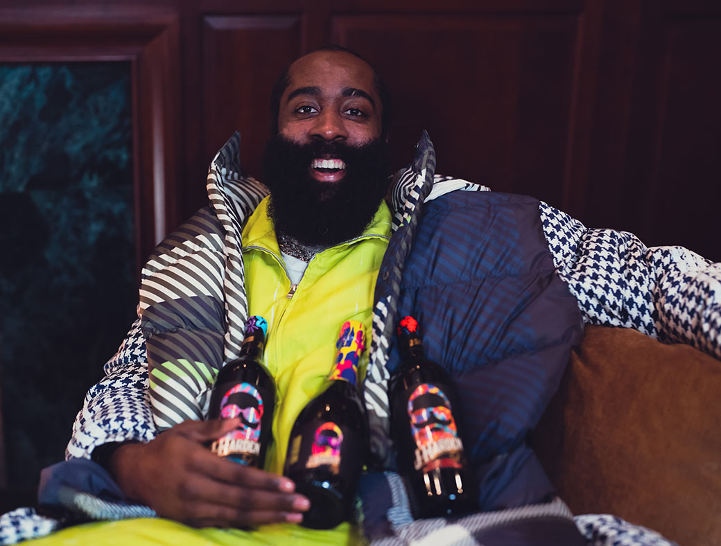 NBA star James Harden sits relaxed on a couch with 3 bottles of his J-Harden wines on his lap